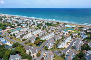 Un quartier résidentiel situé sur la côte, comprenant plusieurs maisons, une piscine et offrant une vue sur l’océan.