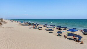 A beach with rows of umbrellas and chairs, a wooden walkway, and the ocean in the background. - 5BR Dog Friendly | Private Pool | Hot Tub | Sauna (Corolla)