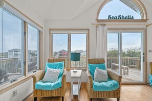 A room with wicker chairs, a small table, and a view of the sea. - 5BR Dog Friendly | Pool | Hot Tub | Balcony (Corolla)