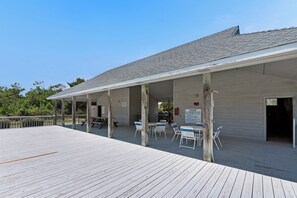 A covered outdoor seating area with tables and chairs, a wooden deck, and a building entrance.