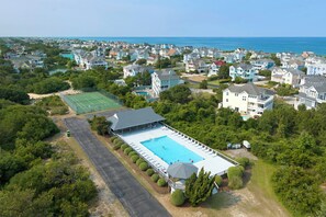 An aerial view of a residential area with a large swimming pool surrounded by houses and greenery.
