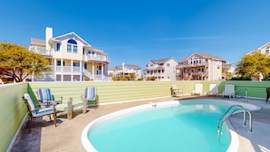 Une piscine avec des chaises longues et, au fond, un bâtiment doté de balcons.