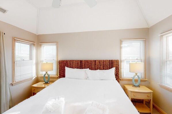 A neatly made bed with white linens, two bedside tables with lamps, and a patterned headboard.