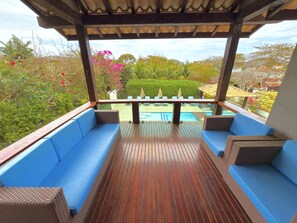 A covered outdoor seating area with blue cushioned benches and a wooden deck. - Pousada Ferradura Boutique (Búzios)