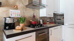 A kitchen with a coffee maker, a pot on the stove, a plant, and a bread on the counter. - Italianway Comfort - Paoli 2 D (Milan)