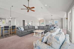 A spacious living area with a large sectional sofa, a coffee table, and a ceiling fan.