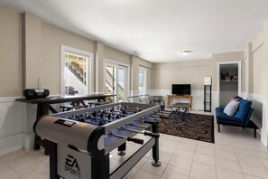 A living room with a foosball table, a television, and a sofa.
