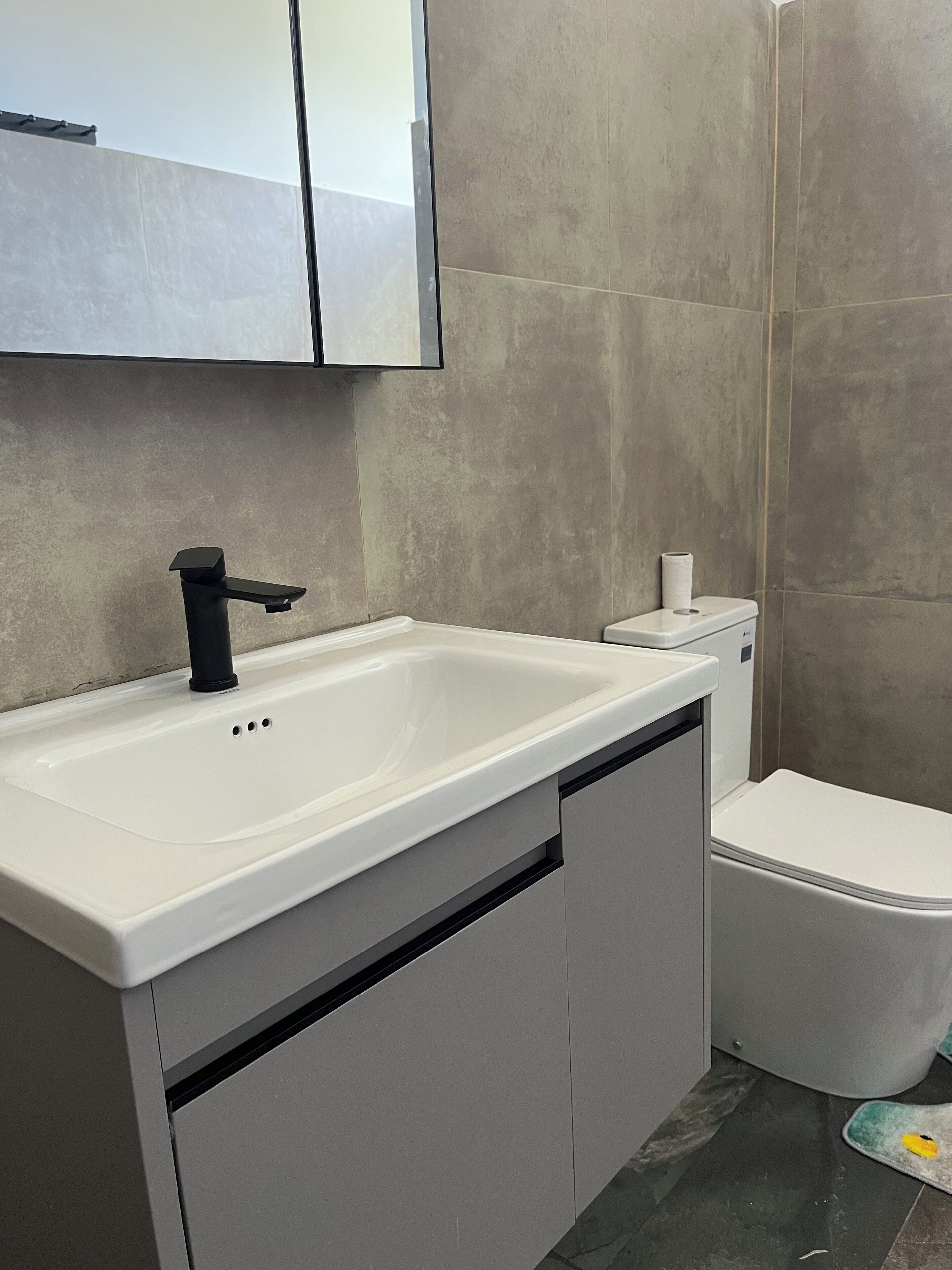 A modern bathroom with a white sink, black faucet, and a toilet.