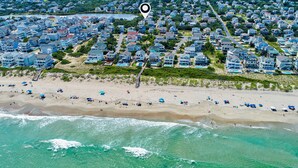 Vista aérea de uma área residencial costeira, com casas, uma praia e um corpo de água.