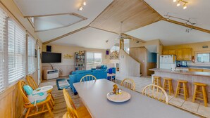 Uma sala ampla com mesa de jantar, cadeiras e espaço de cozinha com banquetas.