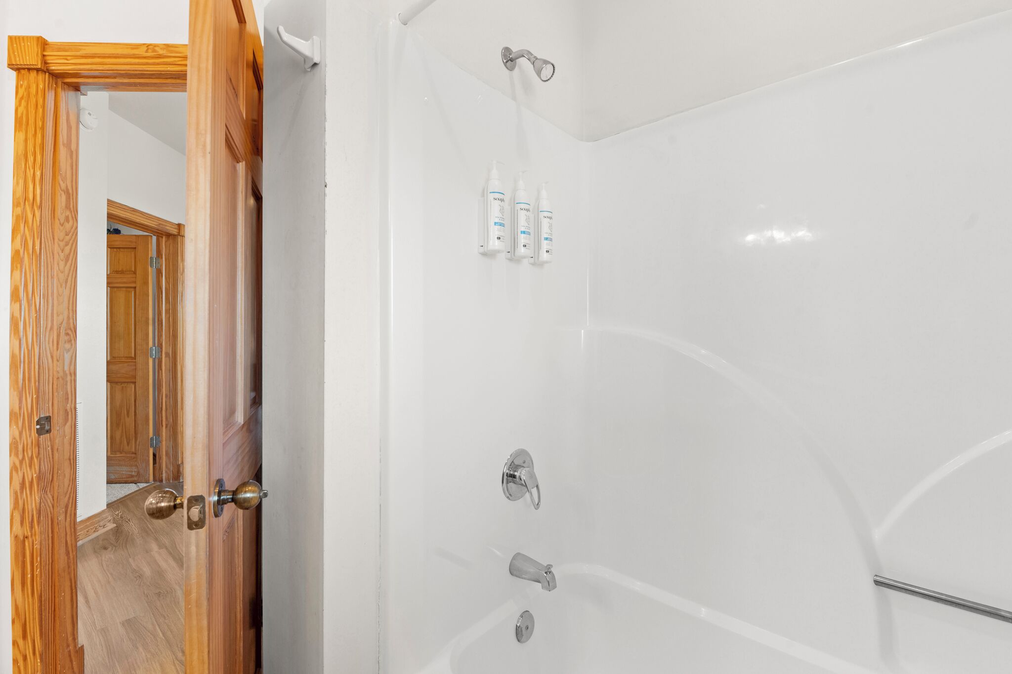 Eine weiße Badewanne mit Duschkopf, einer Handbrause und zwei Shampoo-Flaschen.