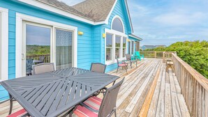 Une maison bleue avec une terrasse, du mobilier d’extérieur et une vue sur le paysage.