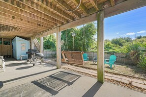 A covered outdoor area with a barbecue setup, seating, and a view of a wooded area. - Spacious water-view 7BR - private pool & hot tub (Corolla)