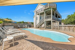 A swimming pool with lounge chairs and a wooden deck area.