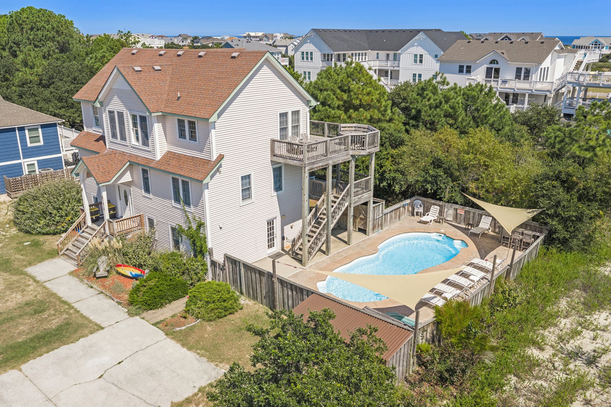 A two-story house with a backyard swimming pool, a deck, and a staircase leading to a second-floor balcony.