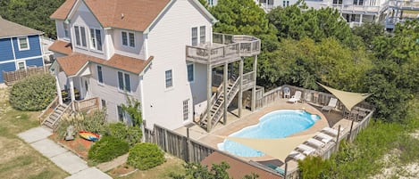 A two-story house with a backyard swimming pool, a deck, and a staircase leading to a second-floor balcony.