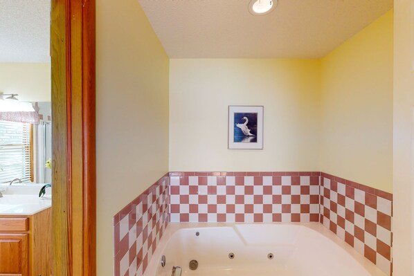 Une salle de bain avec un mur recouvert de carreaux à motifs à carreaux, un tableau encadré représentant un cygne et une porte en bois.