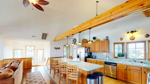 Una cocina amplia con armarios de madera, una isla central y un comedor con sofá y sillas.