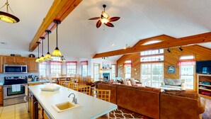 Una cocina amplia con armarios de madera, una isla grande con un fregadero y un ventilador de techo.