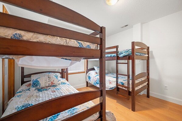 Una habitación con literas, suelo de madera y paredes blancas.