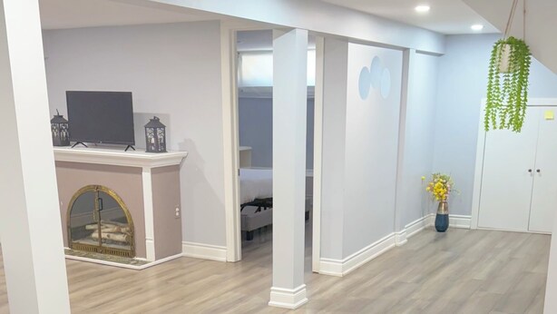 A spacious room with a wooden floor, white walls, and a large window. - Soft landing spot | Relaxed basement hideout (Ajax)
