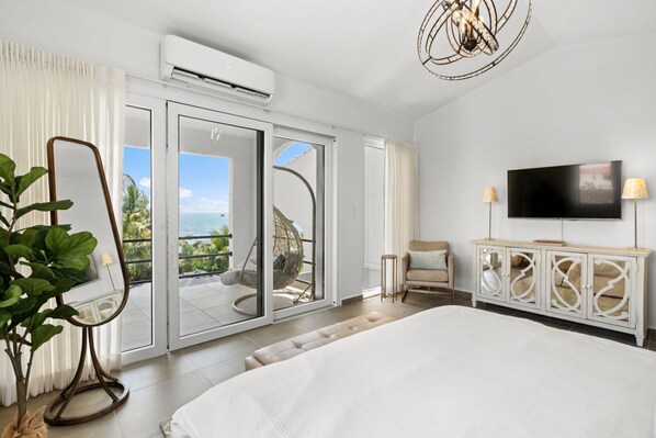 Une chambre dotée d’un grand lit, d’une télévision, d’un balcon avec vue et d’un ventilateur de plafond.