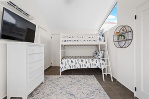 A bedroom with a bunk bed, a TV, a dresser, a patterned rug, and a circular wall decoration. - Beachfront Villa with luxury amenities in Puerto Rico (Humacao)