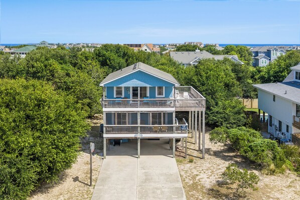 A two-story beachfront house with a balcony, surrounded by greenery and other residential buildings. - Oceanside 3BR, walk to beach & boardwalk (Duck)