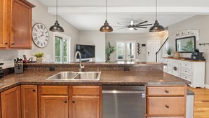 A kitchen with wooden cabinets, a stainless steel sink, and a built-in dishwasher. - KDS0900: BlueDream | Updated | Dog Friendly | Deck | Garage Parking (Kill Devil Hills)