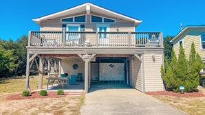 A two-story house with a balcony, a garage, and a covered outdoor seating area.