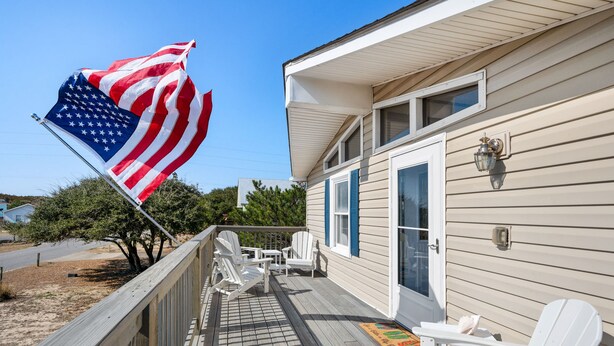 A house with a porch, a flag, and a deck.