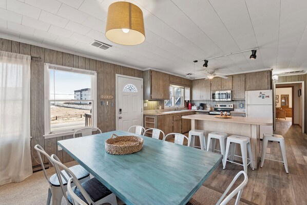 Cozinha moderna com armários de madeira, uma ilha central e um espaço de refeições com mesa e cadeiras.