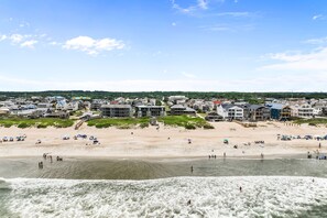 A coastal town with a sandy beach, buildings, and a view of the sea.