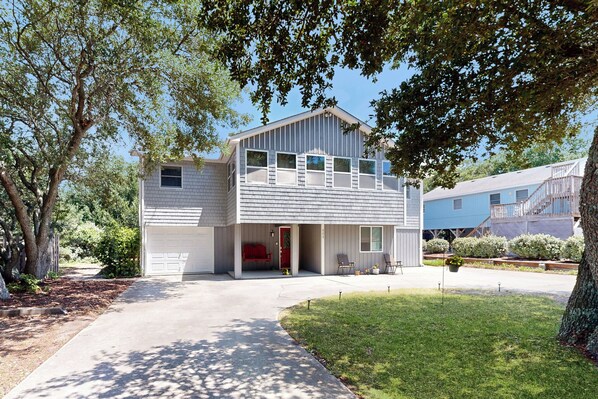A two-story house with a garage, a covered porch, and a well-maintained lawn.