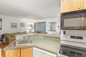 A compact kitchen with a dishwasher, oven, and a sink.