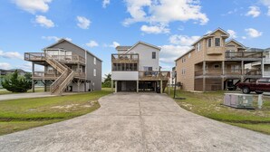 A multi-story residential building with a central entrance, a covered outdoor area, and a staircase leading to an upper level.