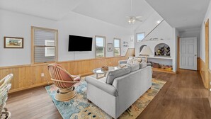 A spacious living room with a grey sofa, wooden flooring, and a ceiling fan.