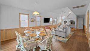 A spacious living area with a dining table, chairs, a sofa, and a television.