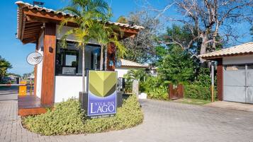 A modern villa with a wooden facade, a sign reading "Vila do Lago," and a paved entrance area with a small garden.