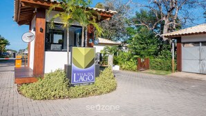 A modern villa with a wooden facade, a sign reading "Vila do Lago," and a paved entrance area with a small garden. - Ap in a Cond. W/pool at Praia do Forte Cvaf0220 (Mata de São João)