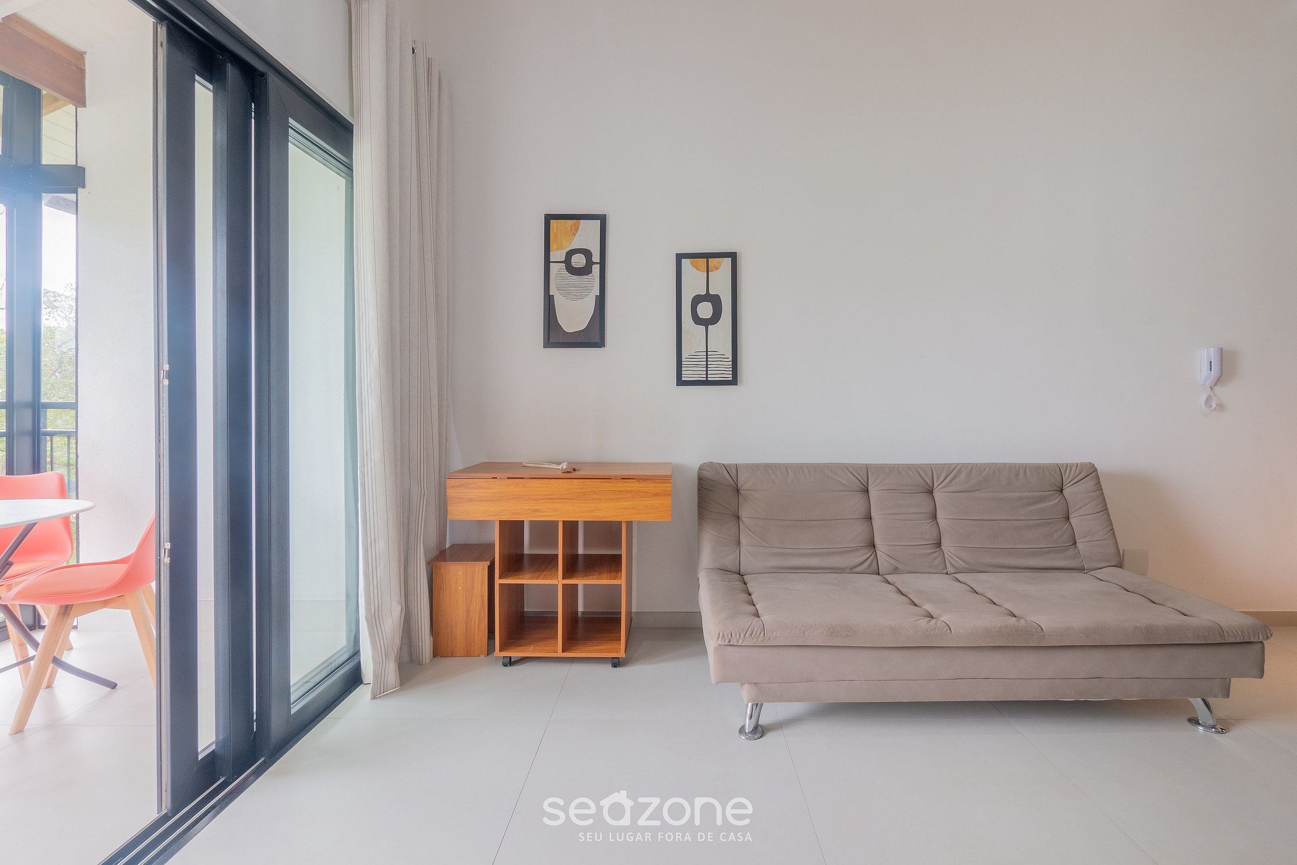 Ein modernes Wohnzimmer mit einer Couch, einem Holztisch und zwei gerahmten Kunstwerken an der Wand.