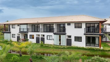 Una casa moderna de dos pisos con techo de tejas, ventanas grandes y un balcón.