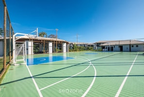 An outdoor basketball court with a net, goalpost, and a building with a roof structure. - Ap in a Cond. W/pool at Praia do Forte Cvaf0220 (Mata de São João)