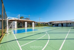 An outdoor basketball court with a net, goalpost, and a building with a roof structure. - Ap in a Cond. W/pool at Praia do Forte Vlp0220 (Mata de São João)