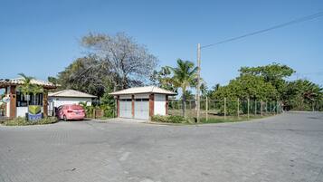 Una propiedad con dos edificios pequeños, un camino de acceso pavimentado y un área cercada con árboles.