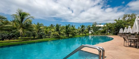 A swimming pool with a clear blue water, surrounded by lush greenery and palm trees.
