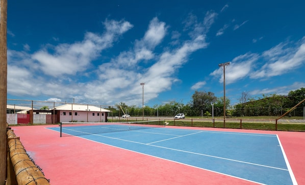 An outdoor tennis court with a net, surrounded by a fence and trees. - Ap in a Cond. W/pool at Praia do Forte Cvaf0220 (Mata de São João)