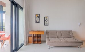 Una sala moderna con un sofá, un escritorio de madera y dos obras de arte enmarcadas en la pared.