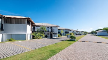 A residential area with modern houses, paved pathways, and a clear sky.