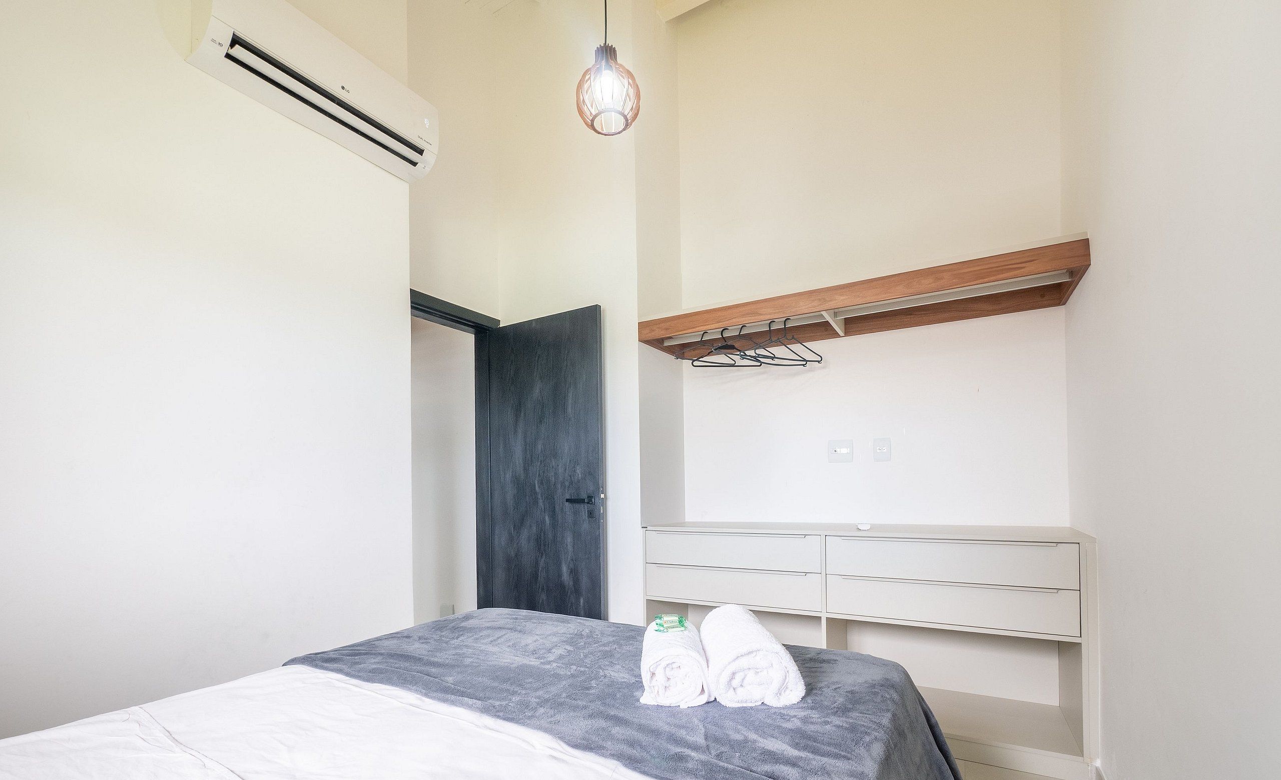 Ein Schlafzimmer mit einem Bett, einem Nachttisch, einer Pendelleuchte und einem Kleiderschrank.